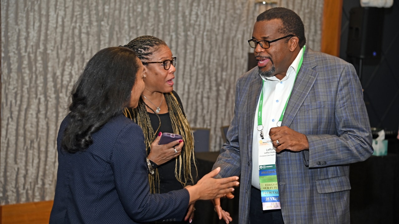 Three SGIM members at an SGIM meeting engaged in animated discussion.