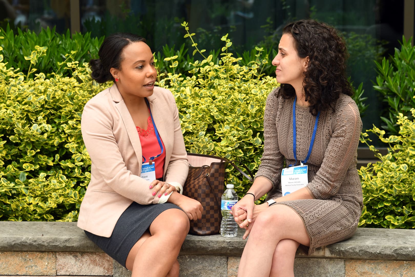 Two women seated outdoors engaged in conversation during a break at an SGIM event.