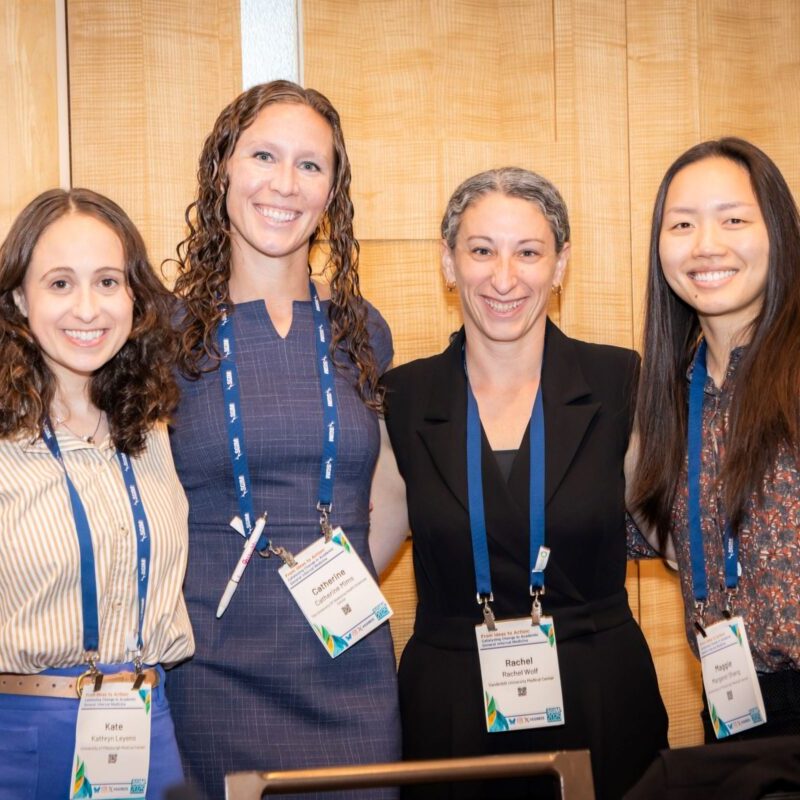 Four conference attendees stand together and smile for a photo
