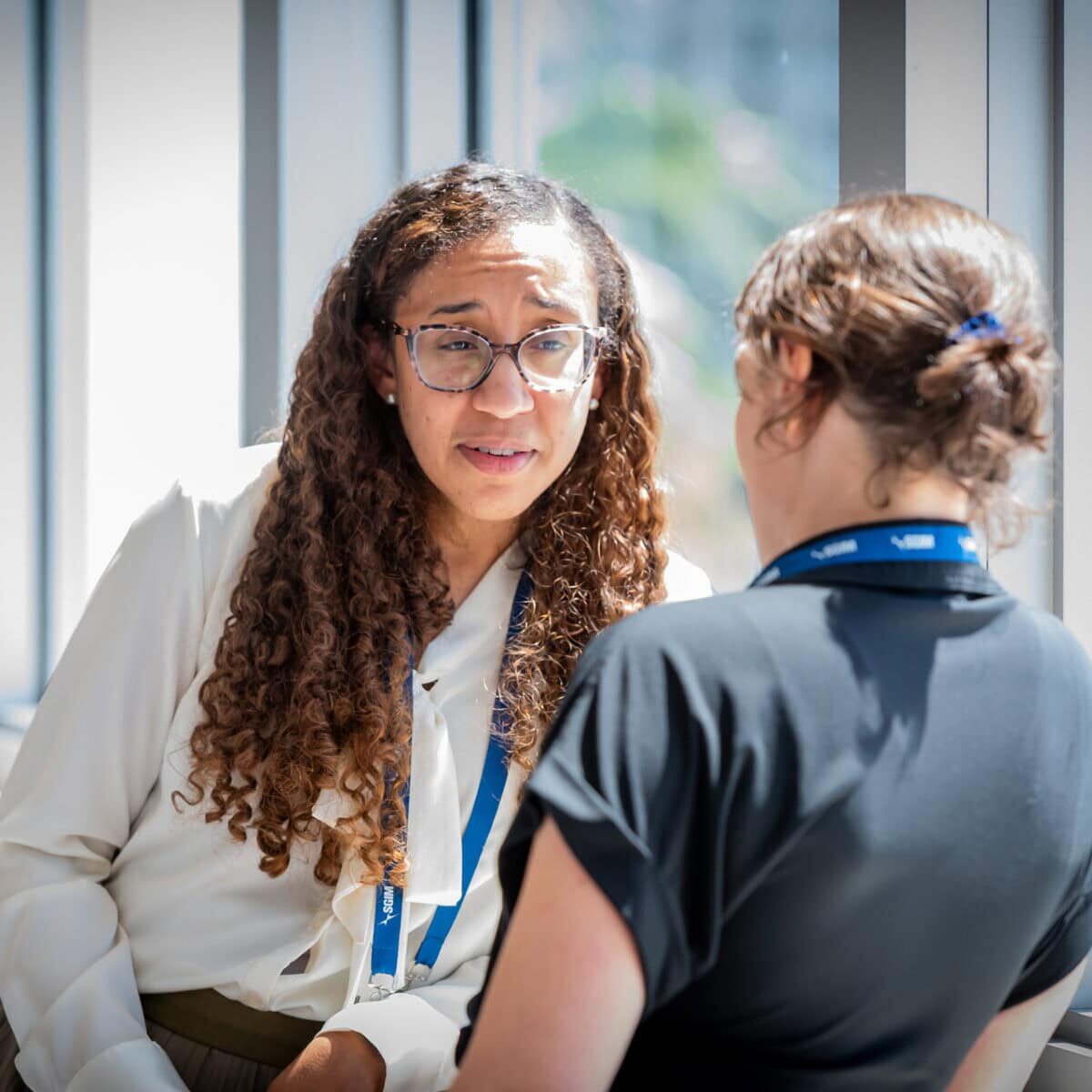 Image of two conference attendees standing by a window, in conversation.