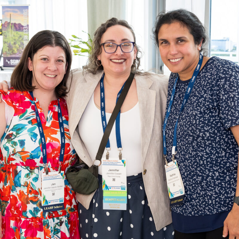 Three conference attendees smiling and posing for a photo
