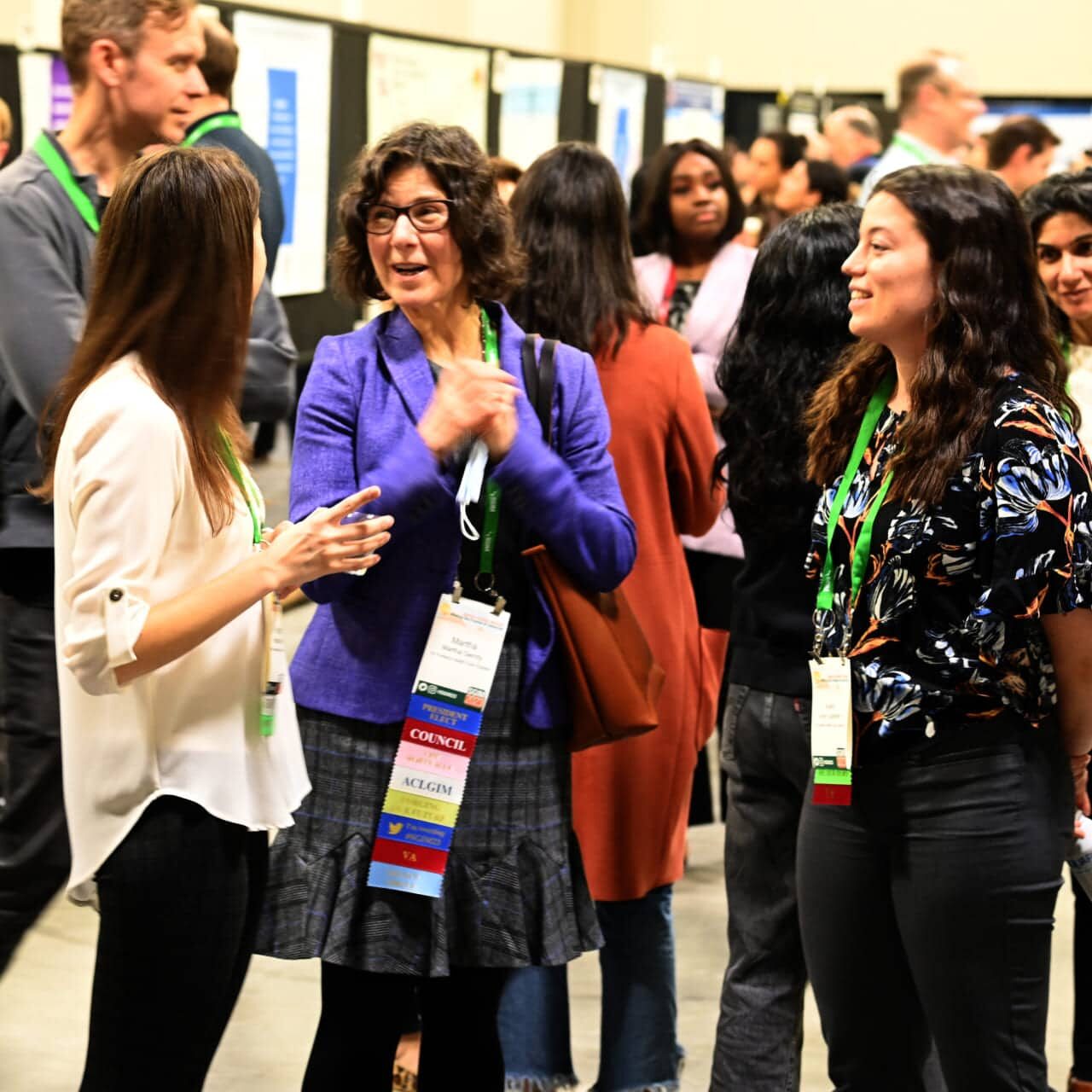 Three meeting attendees reconnecting during a poster session at the SGIM 2023 Annual Meeting