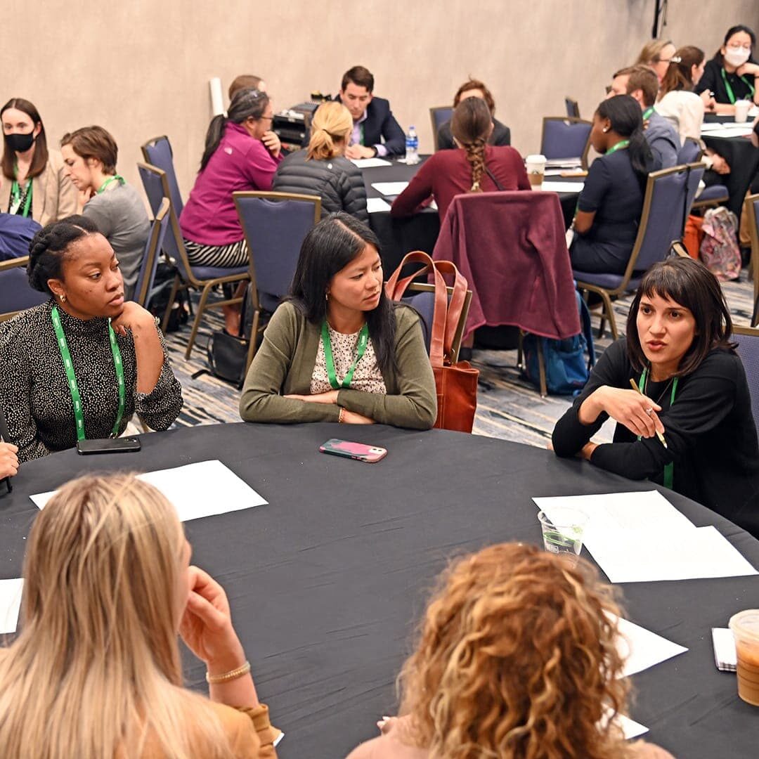 Professionals discussing ideas and sharing insights during SGIM 2023 Conference in a conference room.