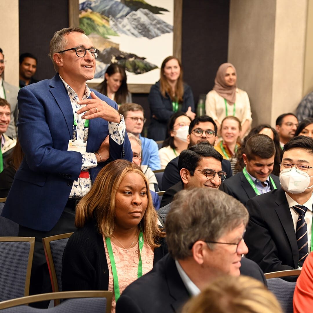 Audience at an SGIM conference, with one participant standing to ask a question.