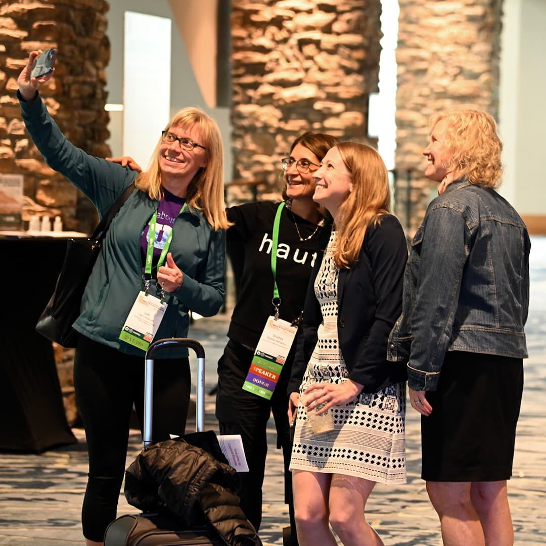 Four SGIM members gathered at an event, capturing a selfie while proudly displaying their SGIM conference attendee badges.