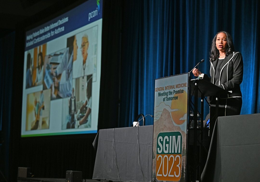 Image of a woman delivering a speech at a podium on stage at the SGIM 2023 Annual Meeting