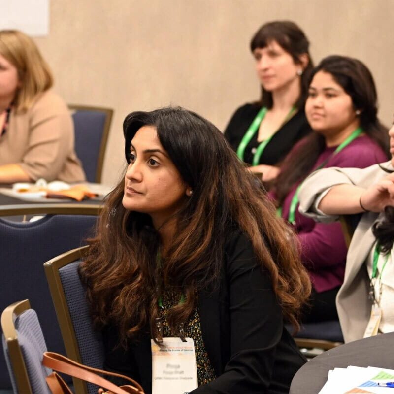 A classroom of adult learners seated and listening to a speaker