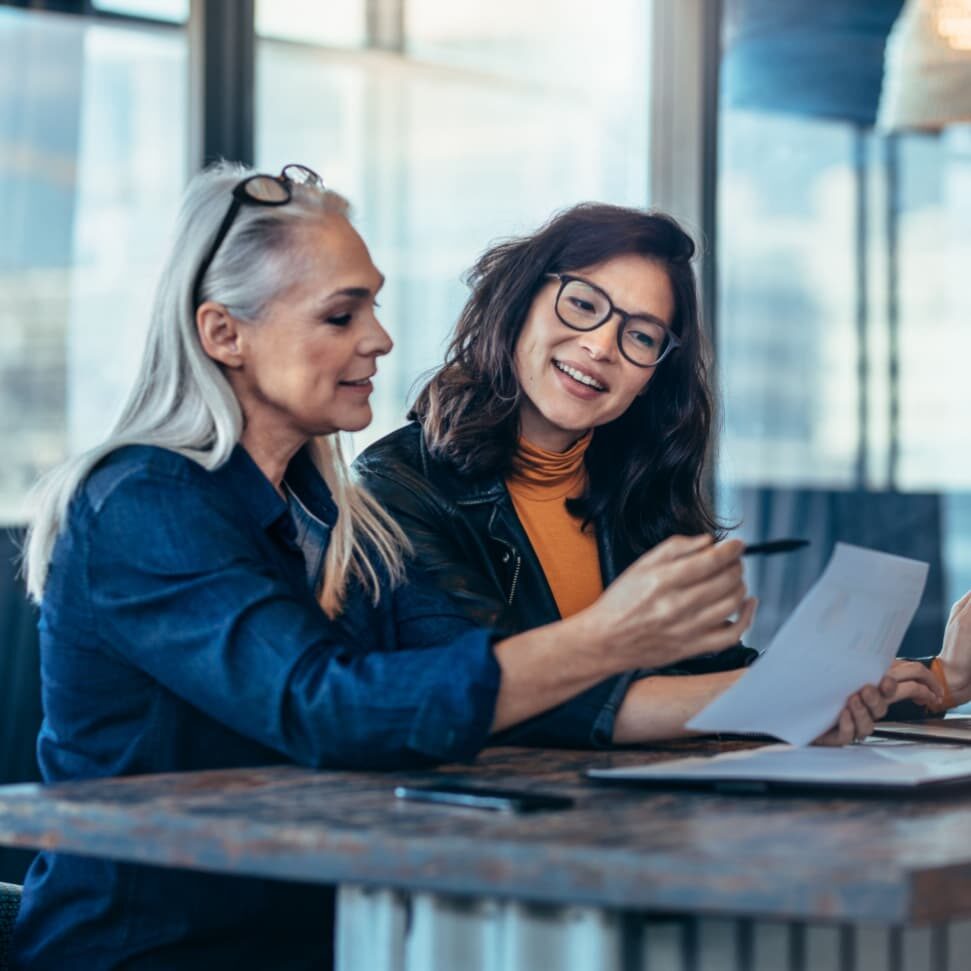 Stock image of two women analyzing a document.