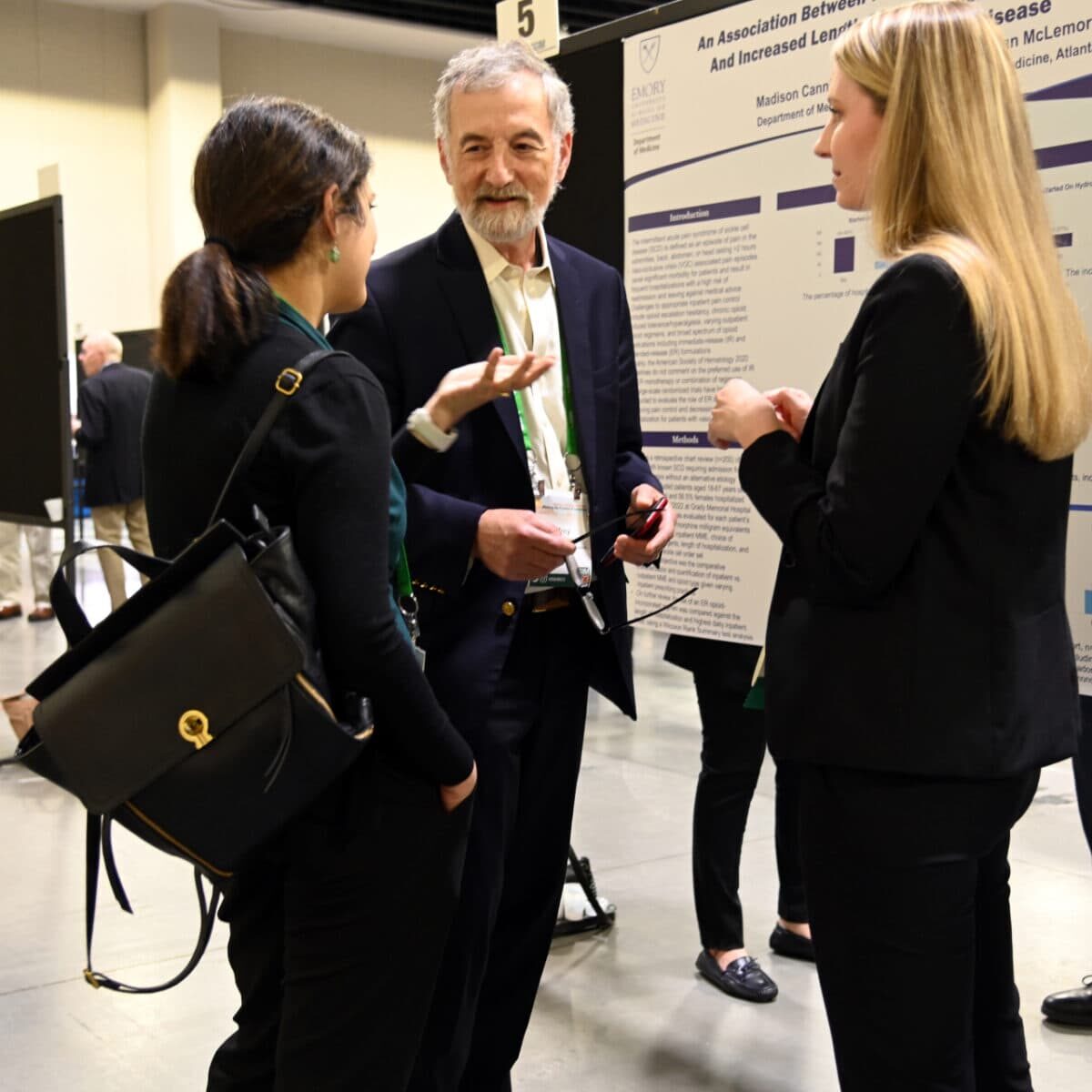 Three SGIM members engaged in a conversation at a conference.