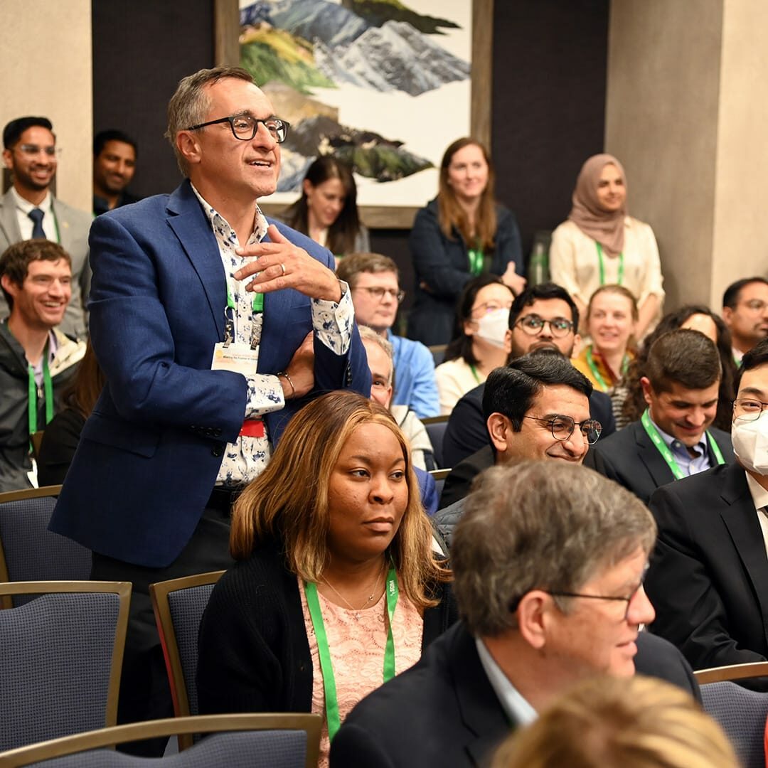 Audience at an SGIM conference, with one participant standing to ask a question.