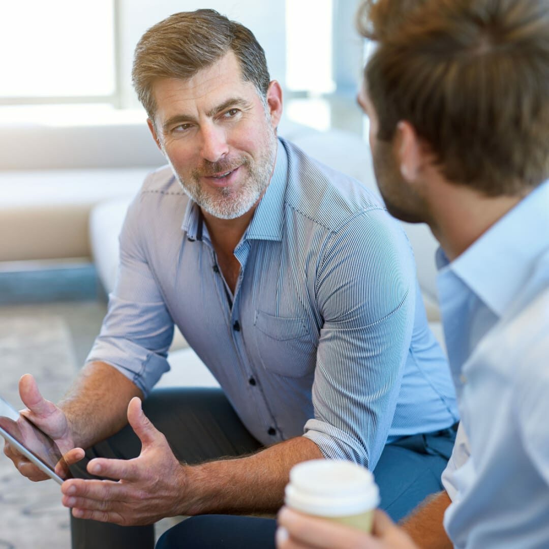 Two corporate individuals engaged in conversation over coffee.