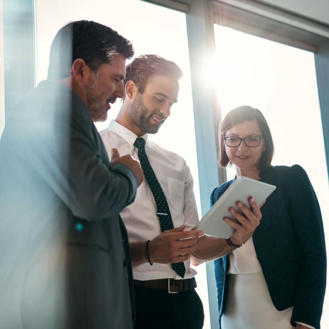 Stock image of three business professionals collaboratively reviewing a document.